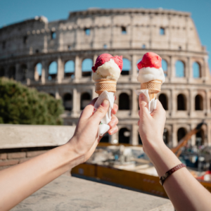 A close-up shot of a couple holding strawberry ice cream up together in Italy. Sweet treats on vacation.